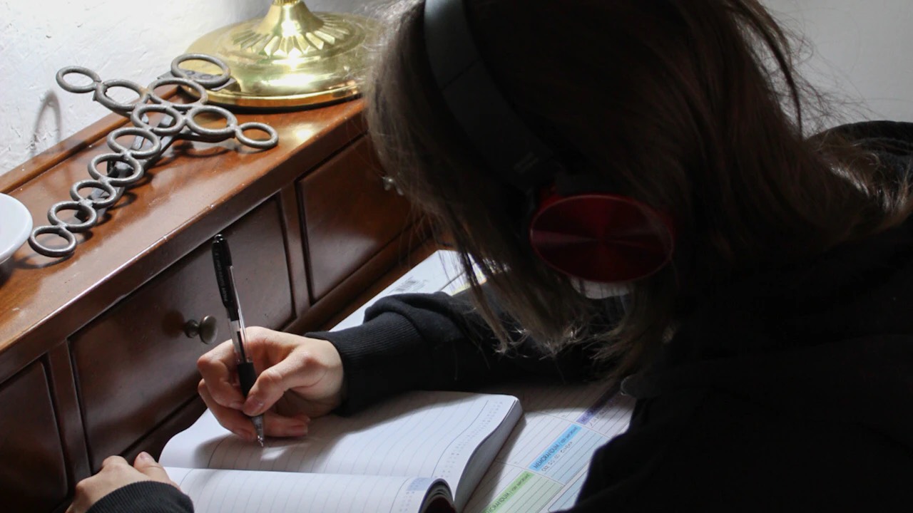 ヘッドホンで英語音声を聞きながらノートに書く学習者
